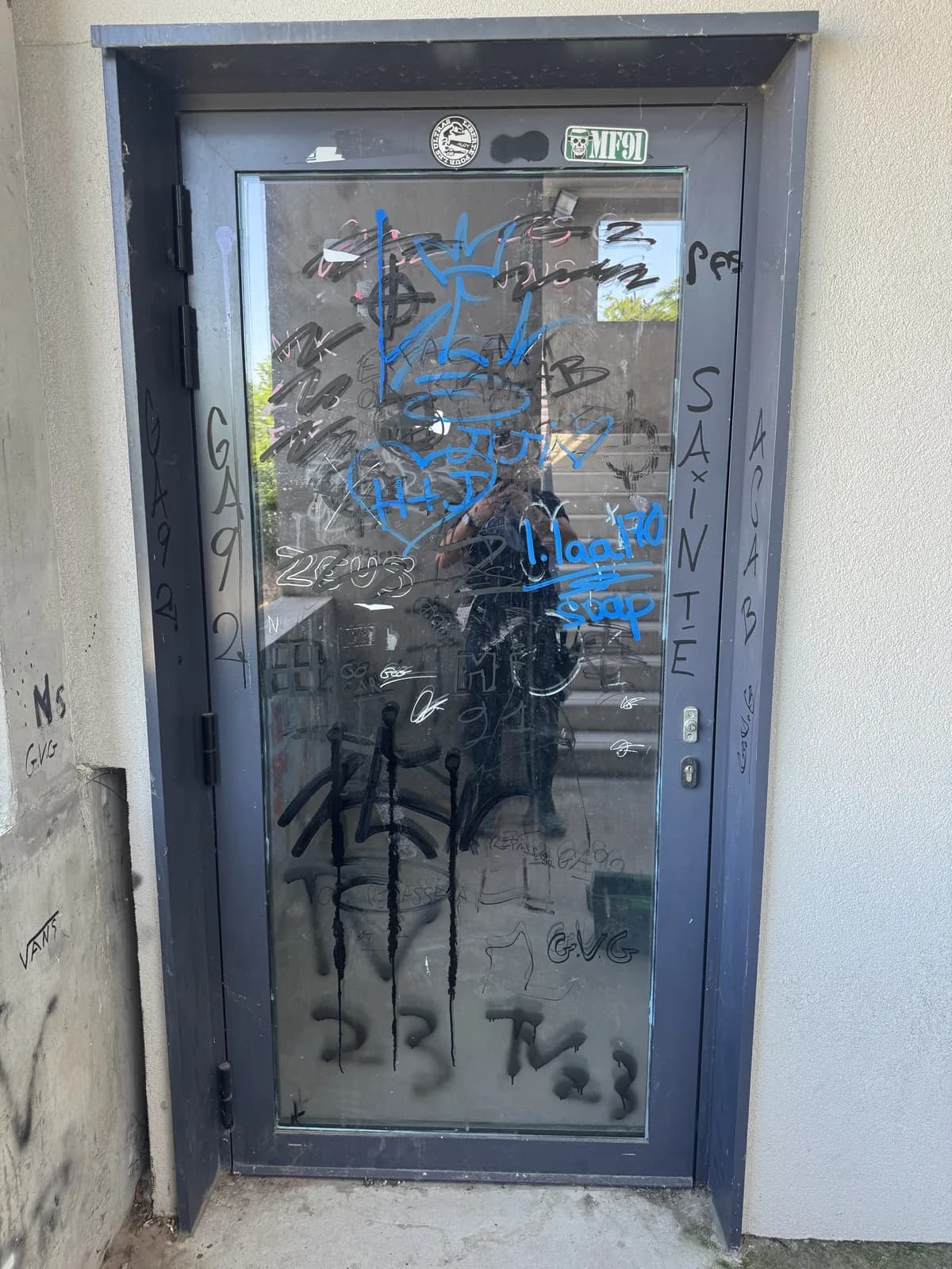 Porte vitrée recouverte de graffitis avant intervention
